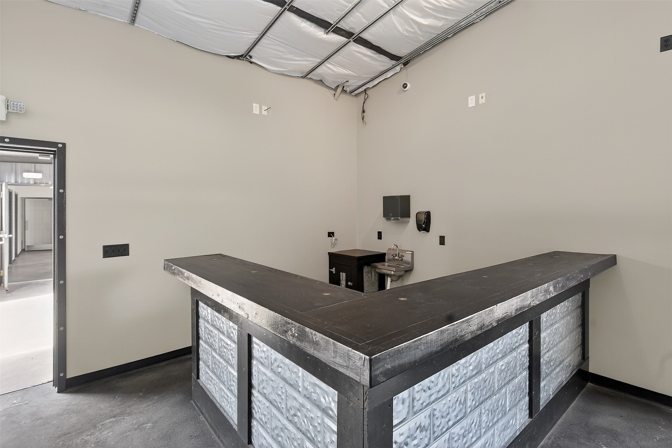Commercial interior with an L-shaped glass-block counter and exposed ceiling framing.