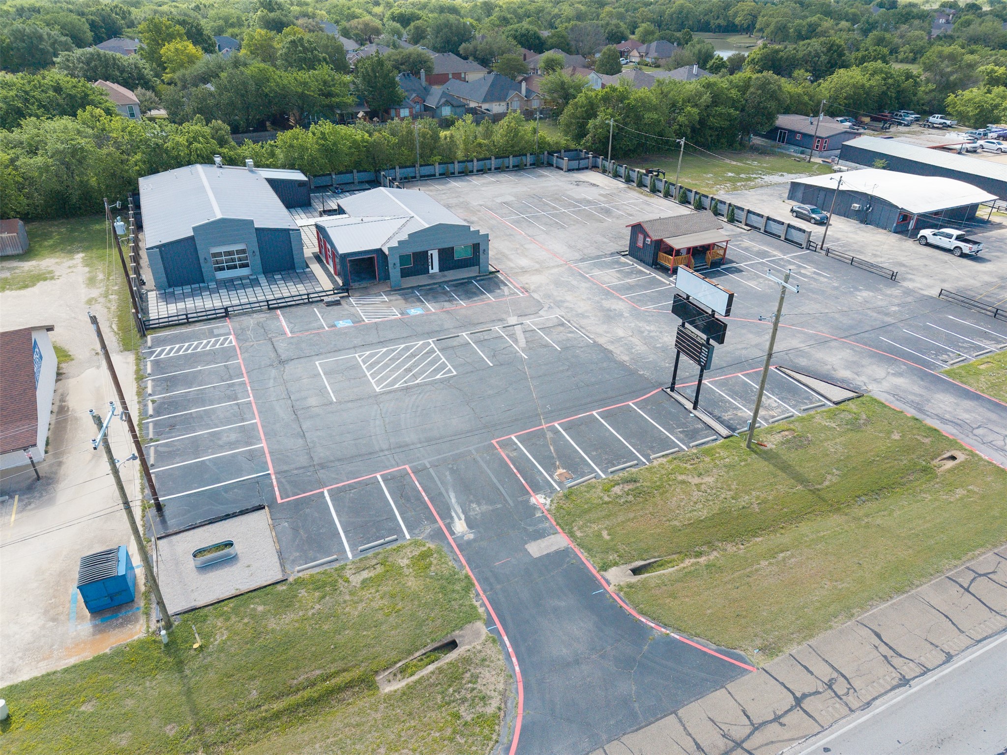 Aerial view of commercial buildings and a large marked parking lot.