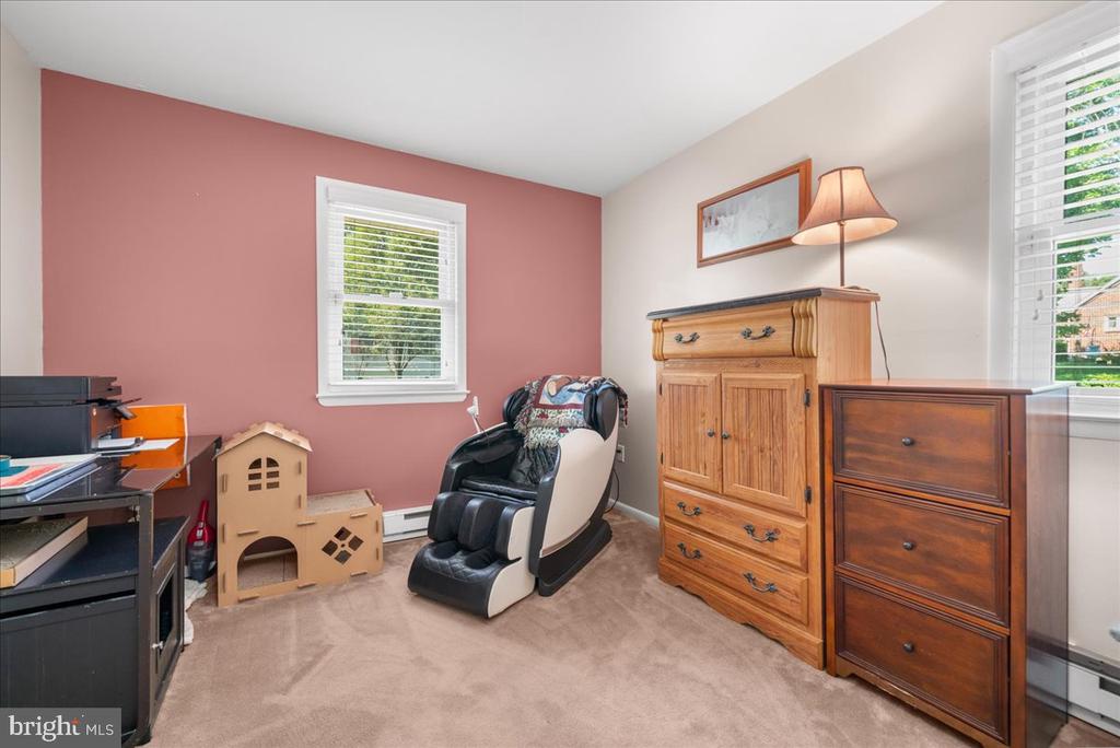 Furnished room with a massage chair, keyboard, wooden dressers, and pink accent wall.