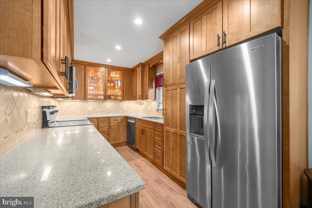 Kitchen with honey-toned wood cabinets, stone counters, and a large stainless steel refrigerator.