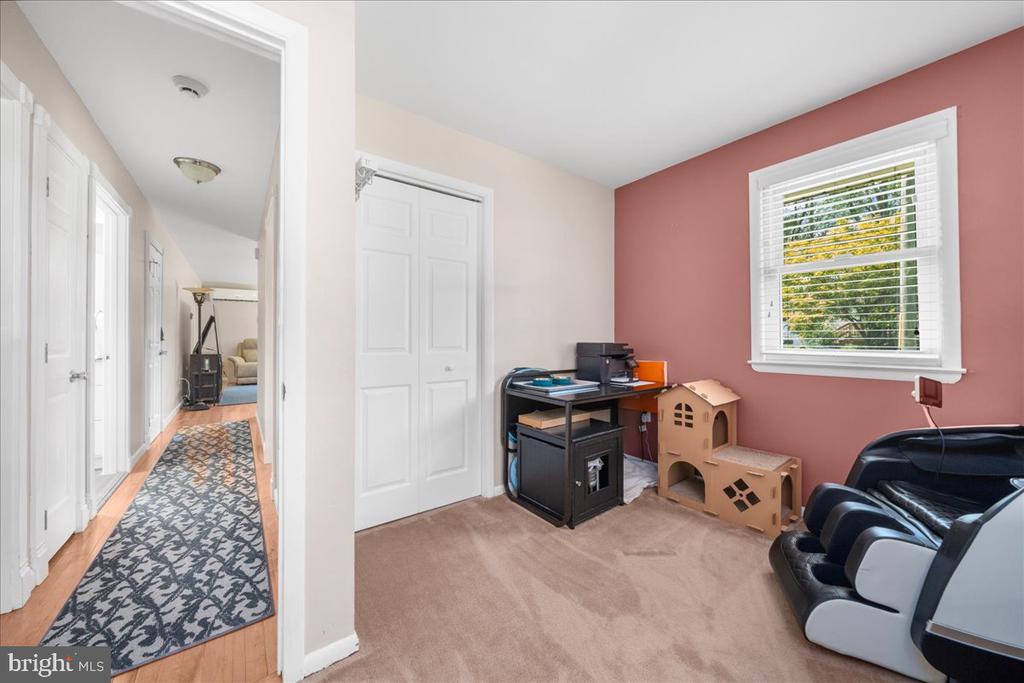 Home office with a pink accent wall, desk, window, and hallway.