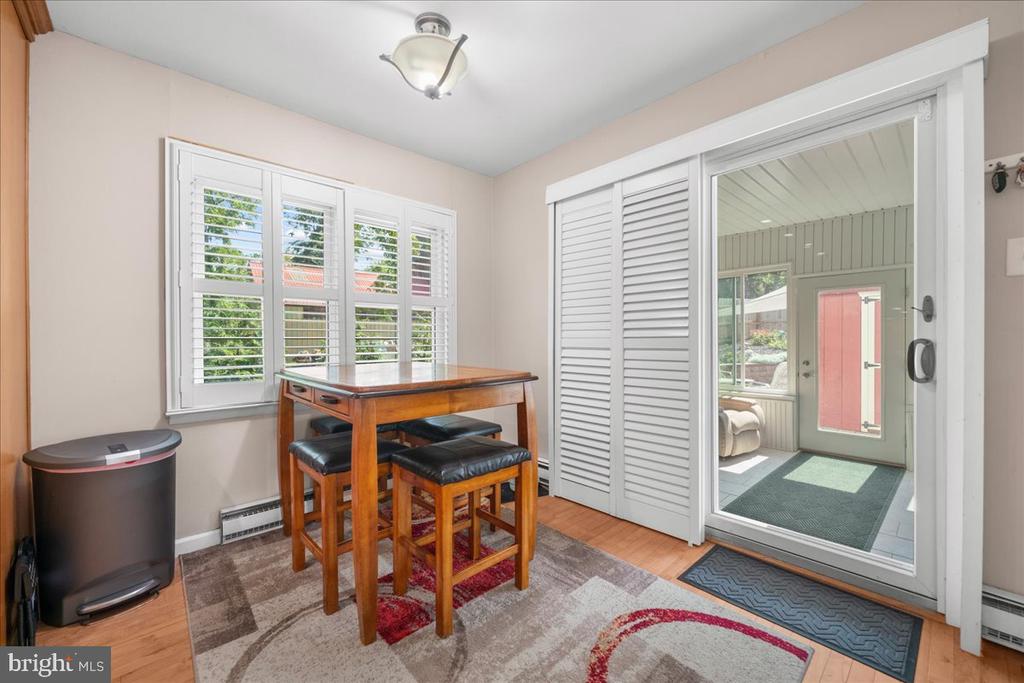 Dining area with a wooden table and stools beside a sliding door to a sunroom.