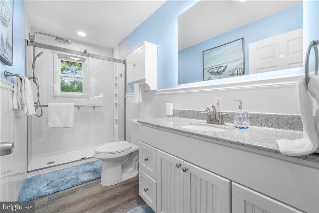 Bathroom with a glass shower, long white vanity, and blue accents.