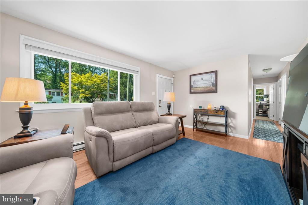 Living room with a gray sofa, blue rug, hardwood floors, and a large picture window.