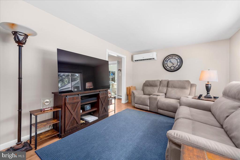 Living room with beige reclining sofas, a large television, and a blue area rug.