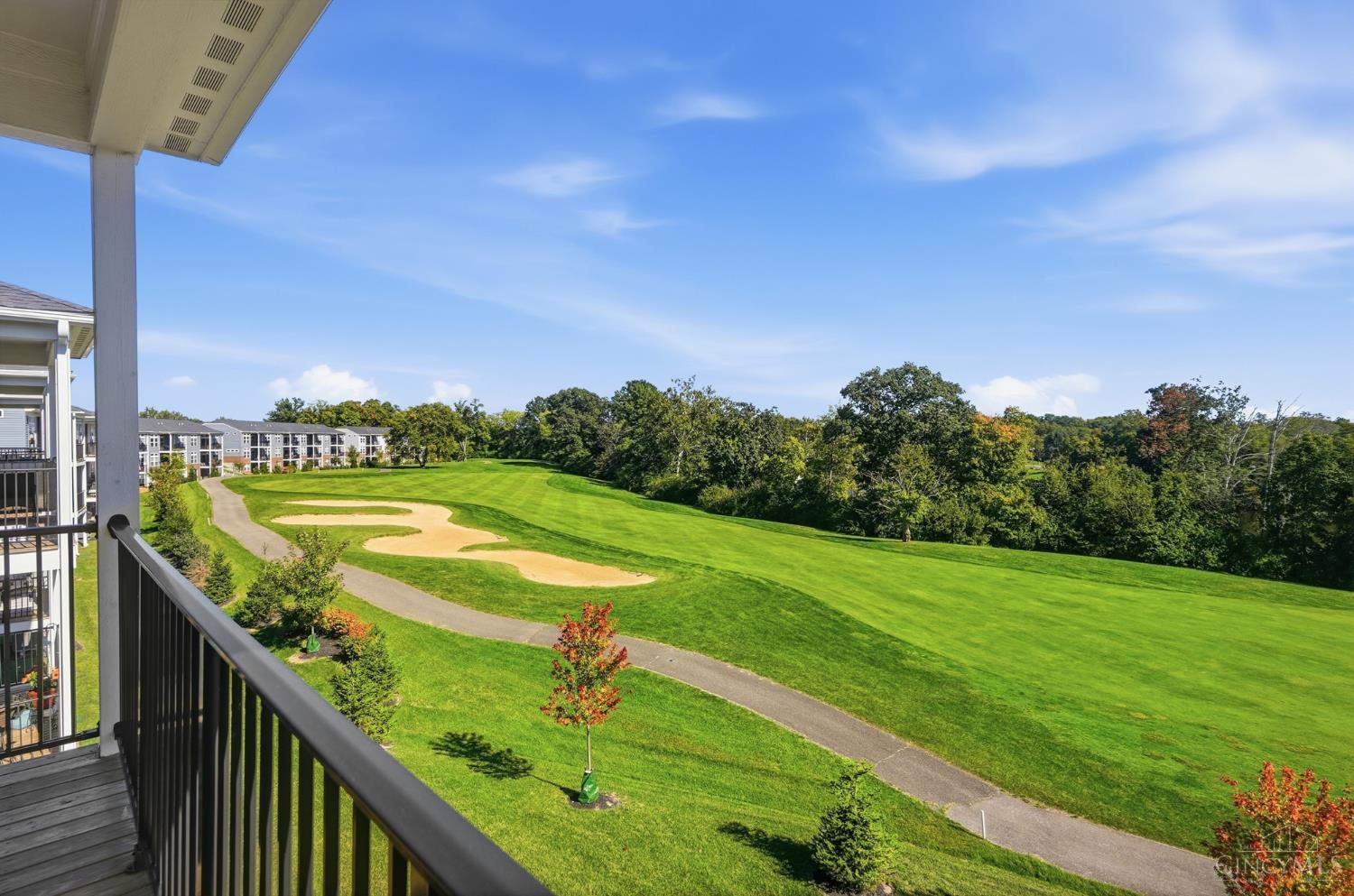 Balcony overlooking a manicured golf course, sand bunker, and tree-lined grounds.