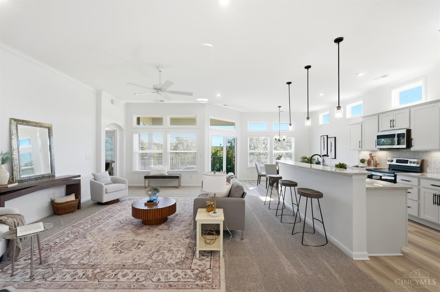 Open living room and kitchen with a long island, bar stools, and large windows.
