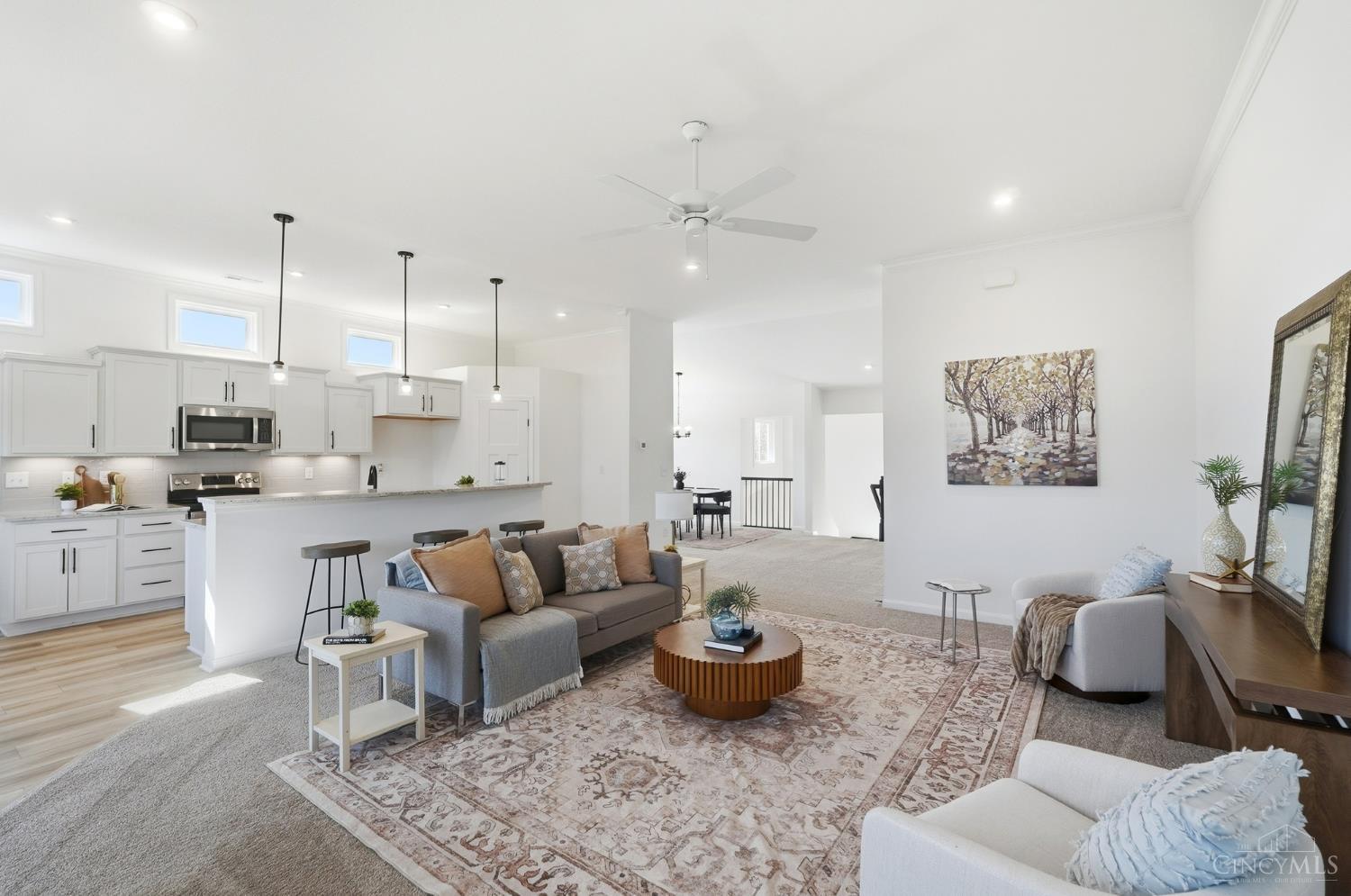 Open-plan living room and kitchen with a long island, gray sofas, and a patterned rug.