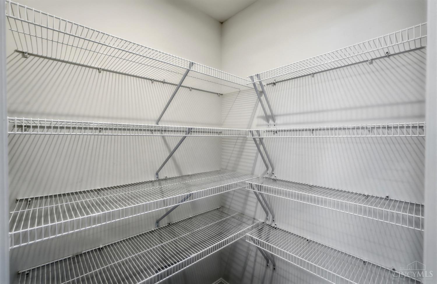 Walk-in closet with white wire shelves lining three walls.