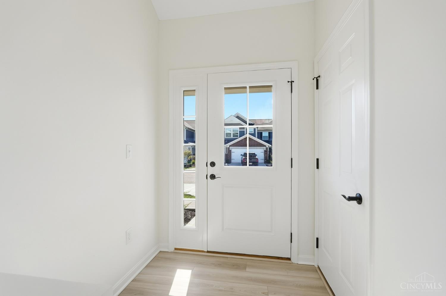 Unfurnished entryway with a white front door, sidelights, and light wood-look flooring.