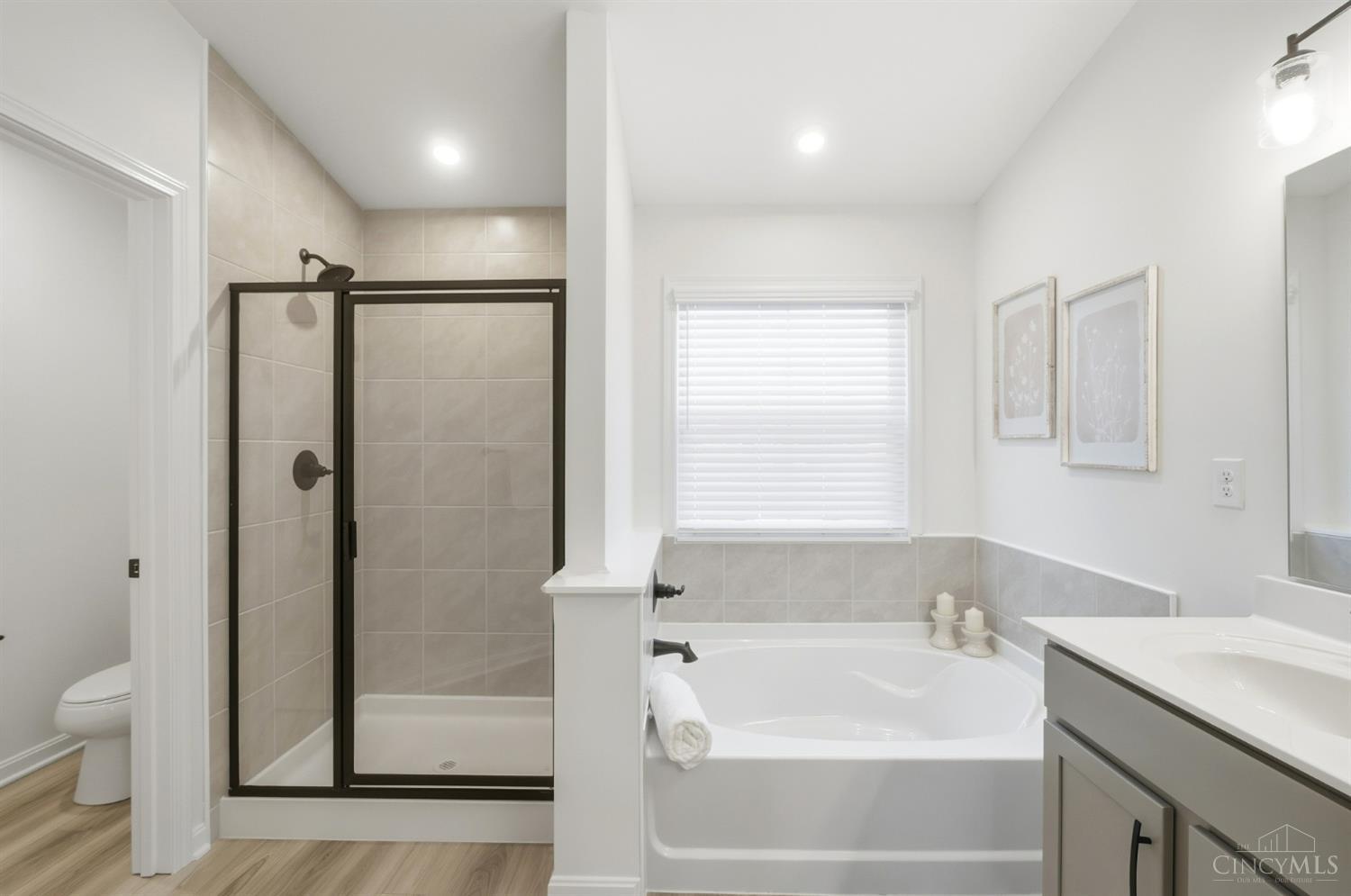 Bathroom with a black-framed glass shower, soaking tub, and gray vanity.