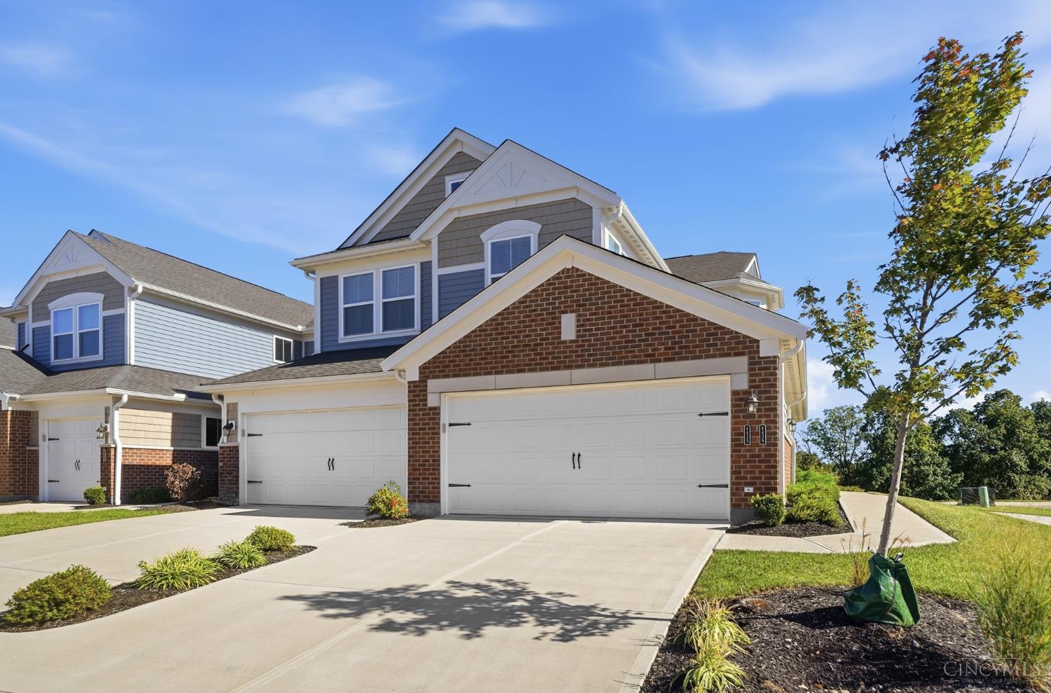 Two-story home with gray siding, brick accents, and a wide double garage.