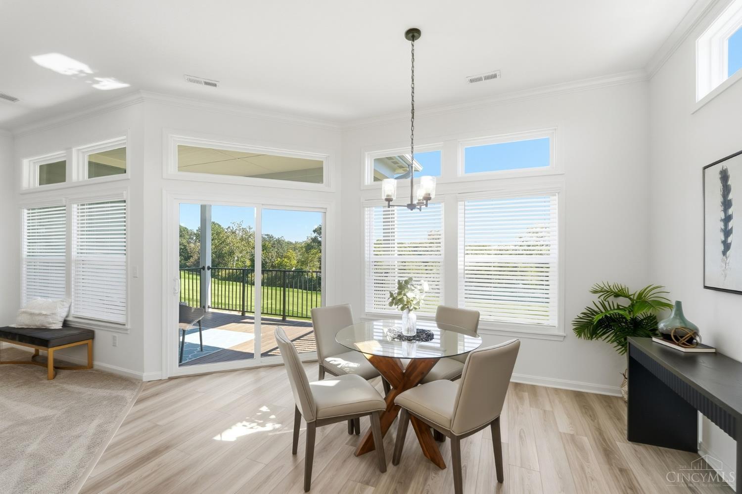 Dining area with a round glass table, large windows, and sliding doors to a deck and lawn.