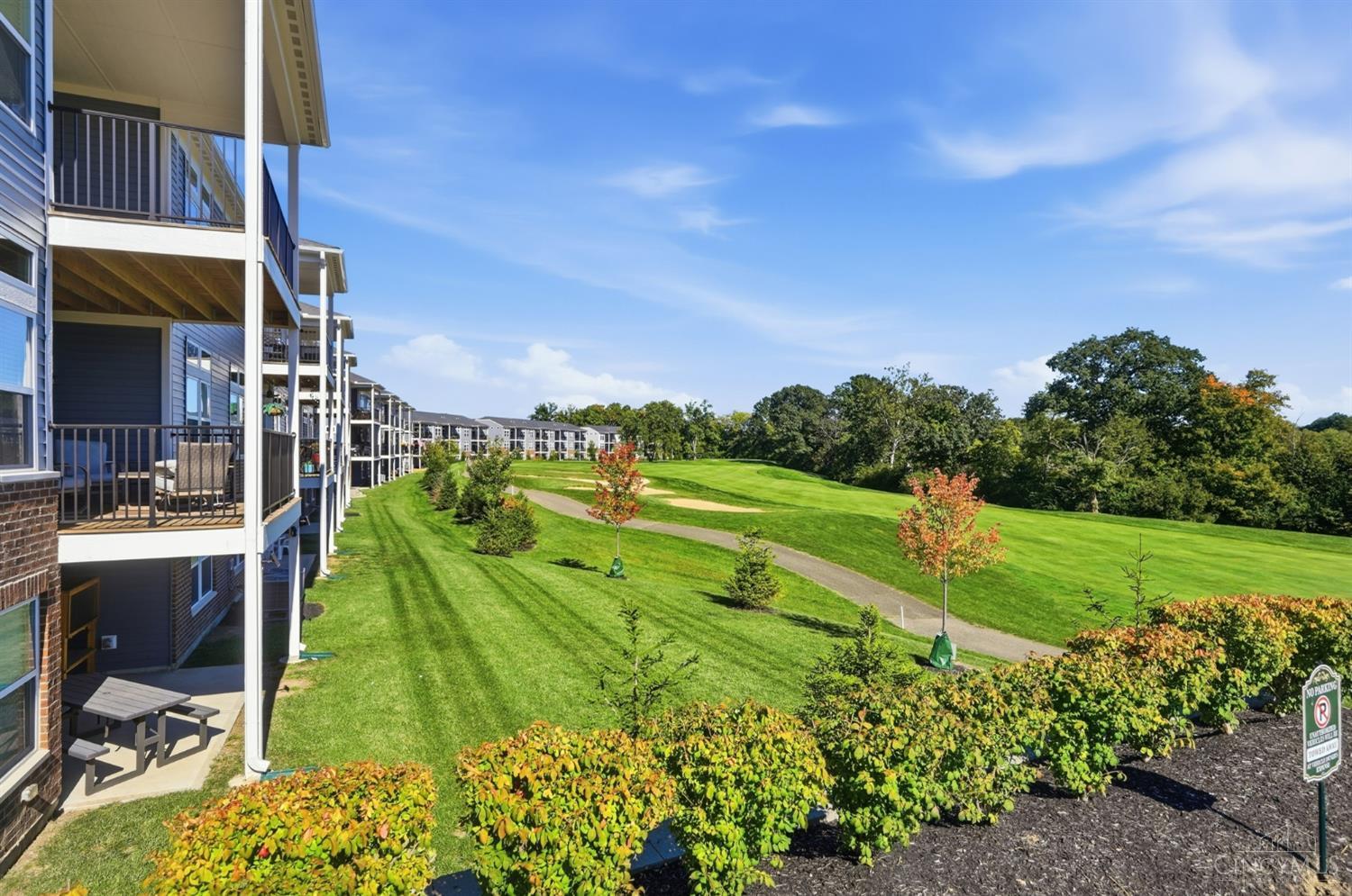 Condominiums with private balconies overlook a landscaped green lawn and curving path.