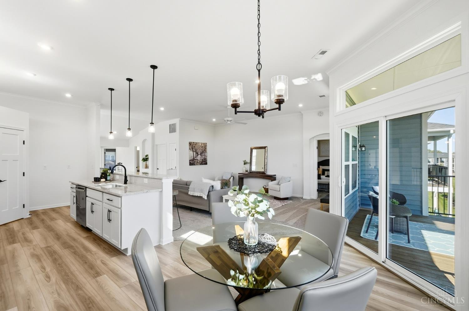 Open-plan kitchen, dining area, and living room with a round glass table and sliding doors to a covered deck.