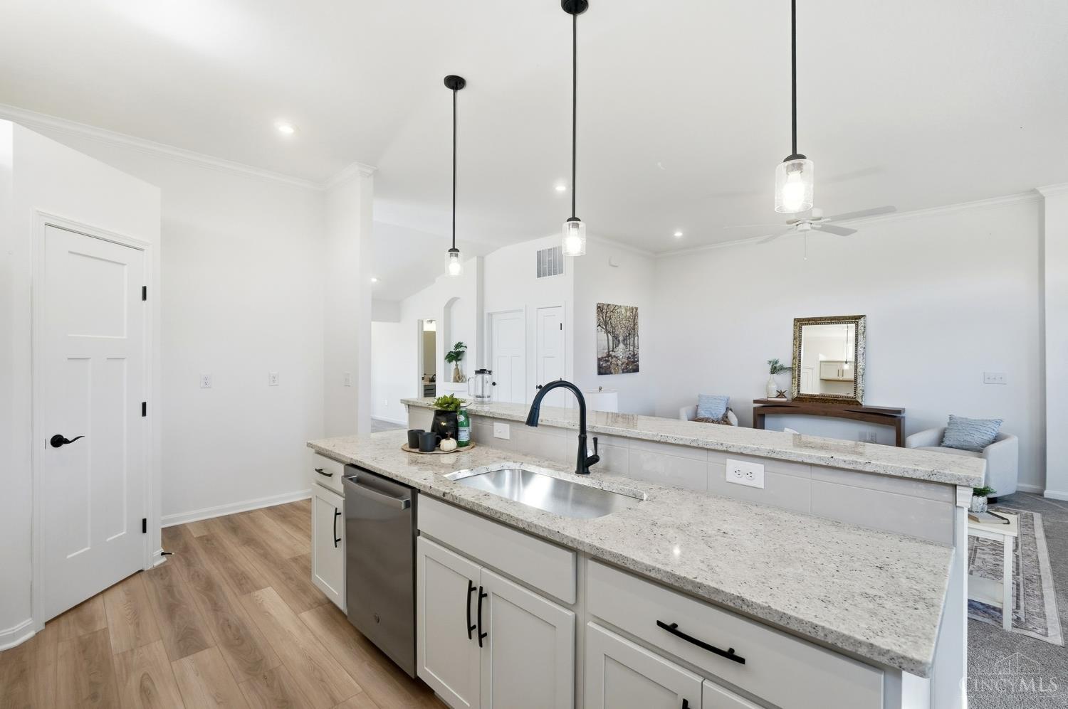 Bright open kitchen with a stone island, undermount sink, black faucet, and adjoining furnished living area.