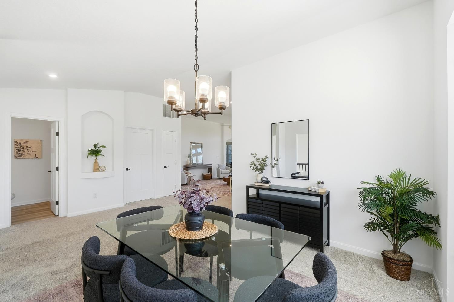Staged dining room with a glass table, upholstered chairs, and modern chandelier.