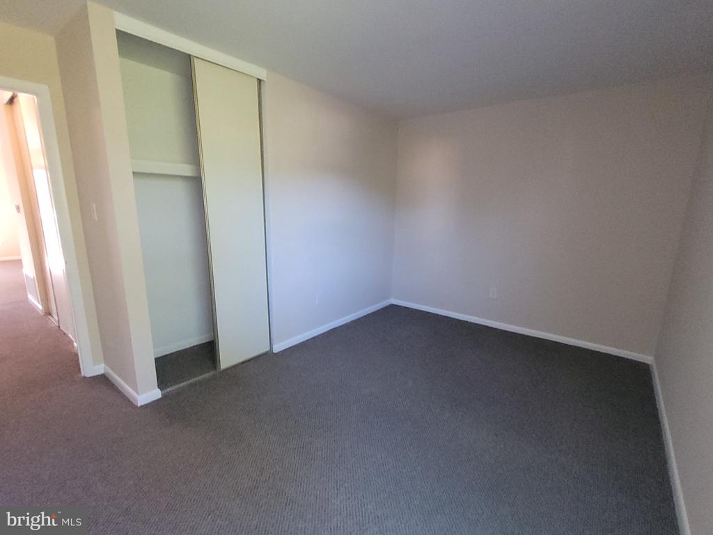 Empty bedroom with gray carpet and a sliding-door closet.