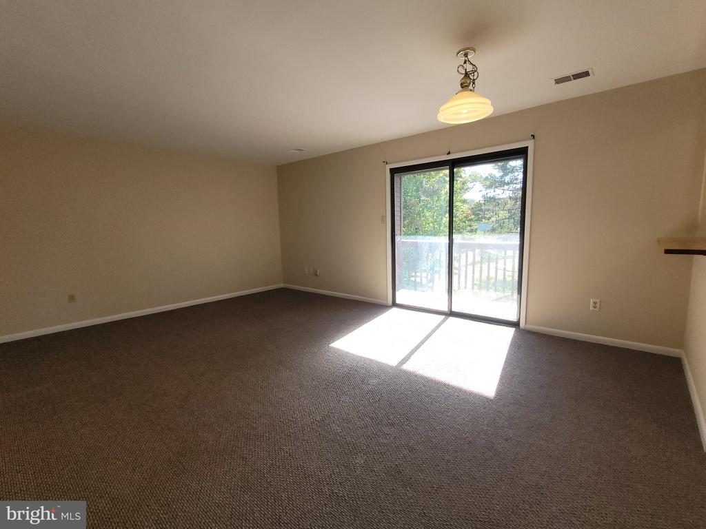 Empty carpeted room with a sliding glass door opening onto a deck or balcony.
