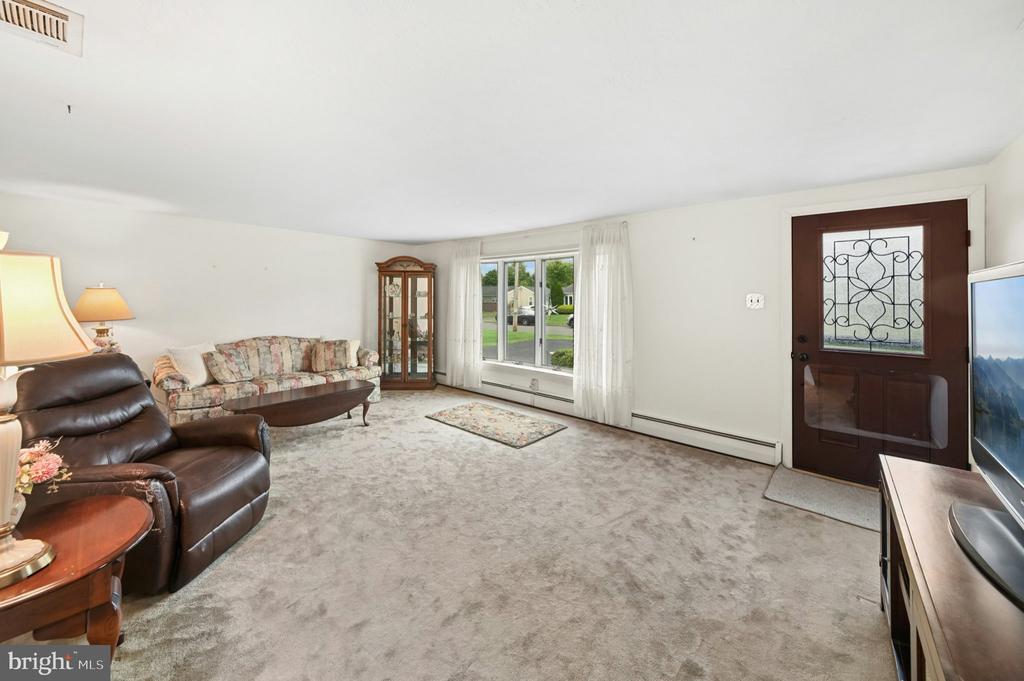 Living room with a brown leather recliner, floral sofa, and decorative-glass front door.