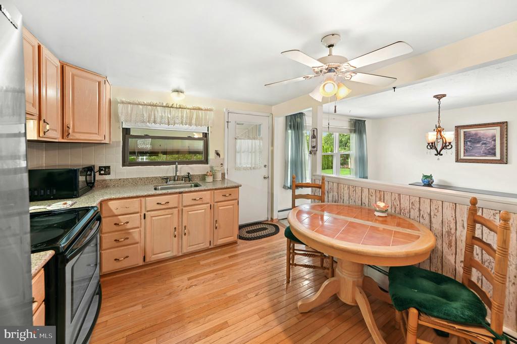 Kitchen and dining area with light wood cabinets and a round tiled table.