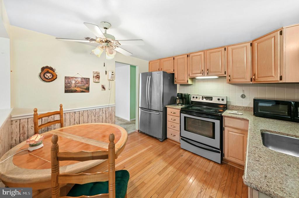 Kitchen with light wood cabinets, stainless steel appliances, granite counters, and a round dining table.