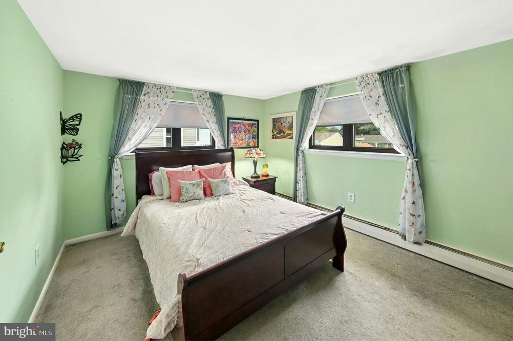 Bedroom with a dark wood bed, pale green walls, and two curtained windows.