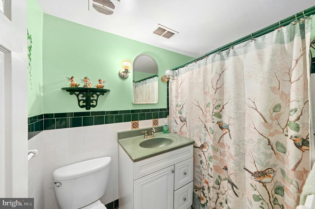 Bathroom with a green vanity, mint walls, and a bird-patterned shower curtain.