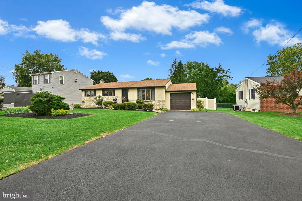 Single-story home with stone accents, attached garage, broad driveway, and landscaped lawn.