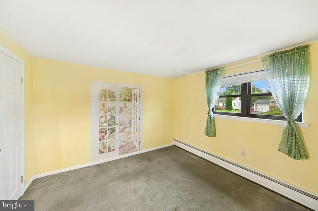 Empty yellow bedroom with gray carpet, green curtains, and garden-themed closet doors.
