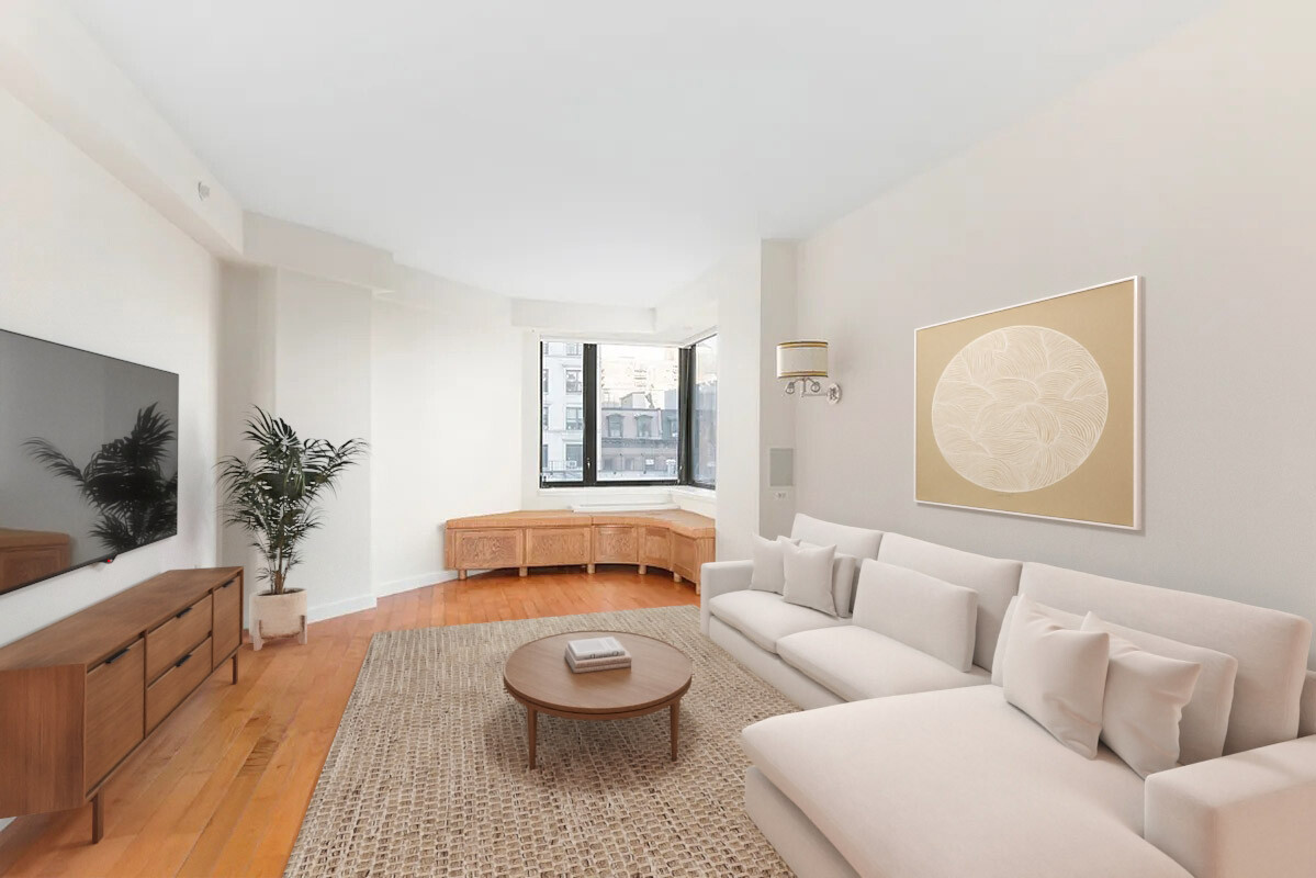 Bright living room with a white sectional, wood floors, and a window overlooking nearby buildings.