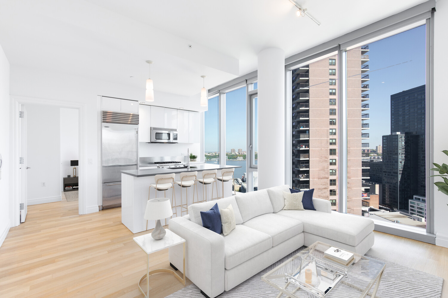Bright condo living room with a white sectional and floor-to-ceiling windows overlooking the city.