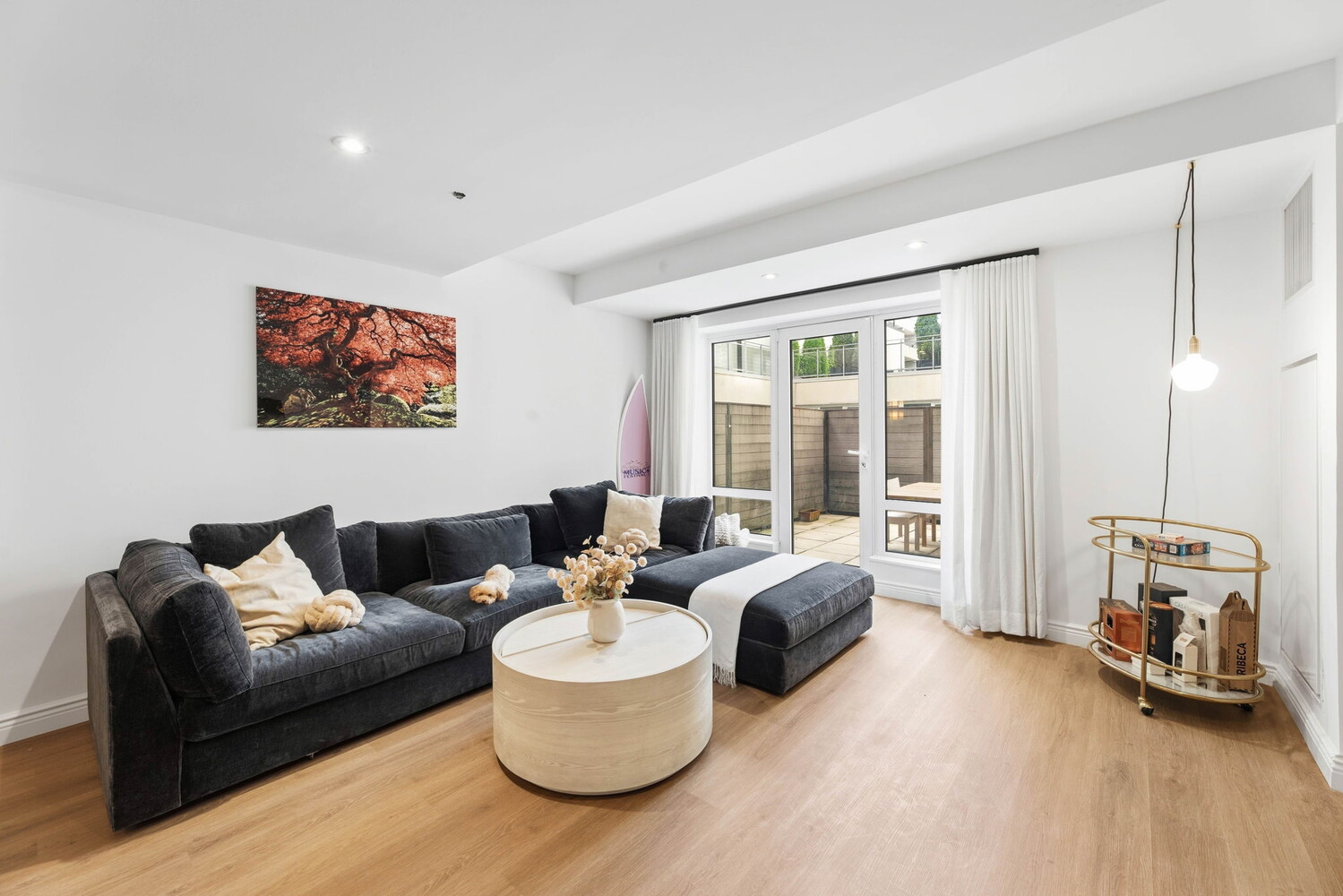 Living room with a charcoal sectional, round coffee table, and glass doors opening to a patio.
