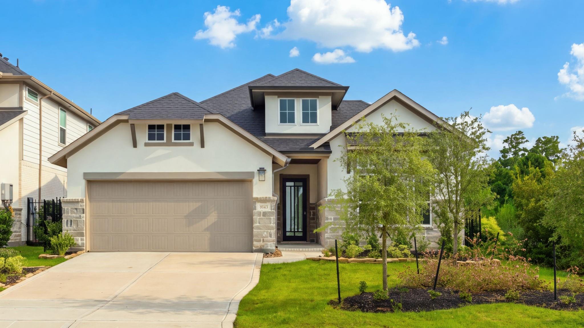 Two-story house with a stone-accented facade, two-car garage, and landscaped front yard.