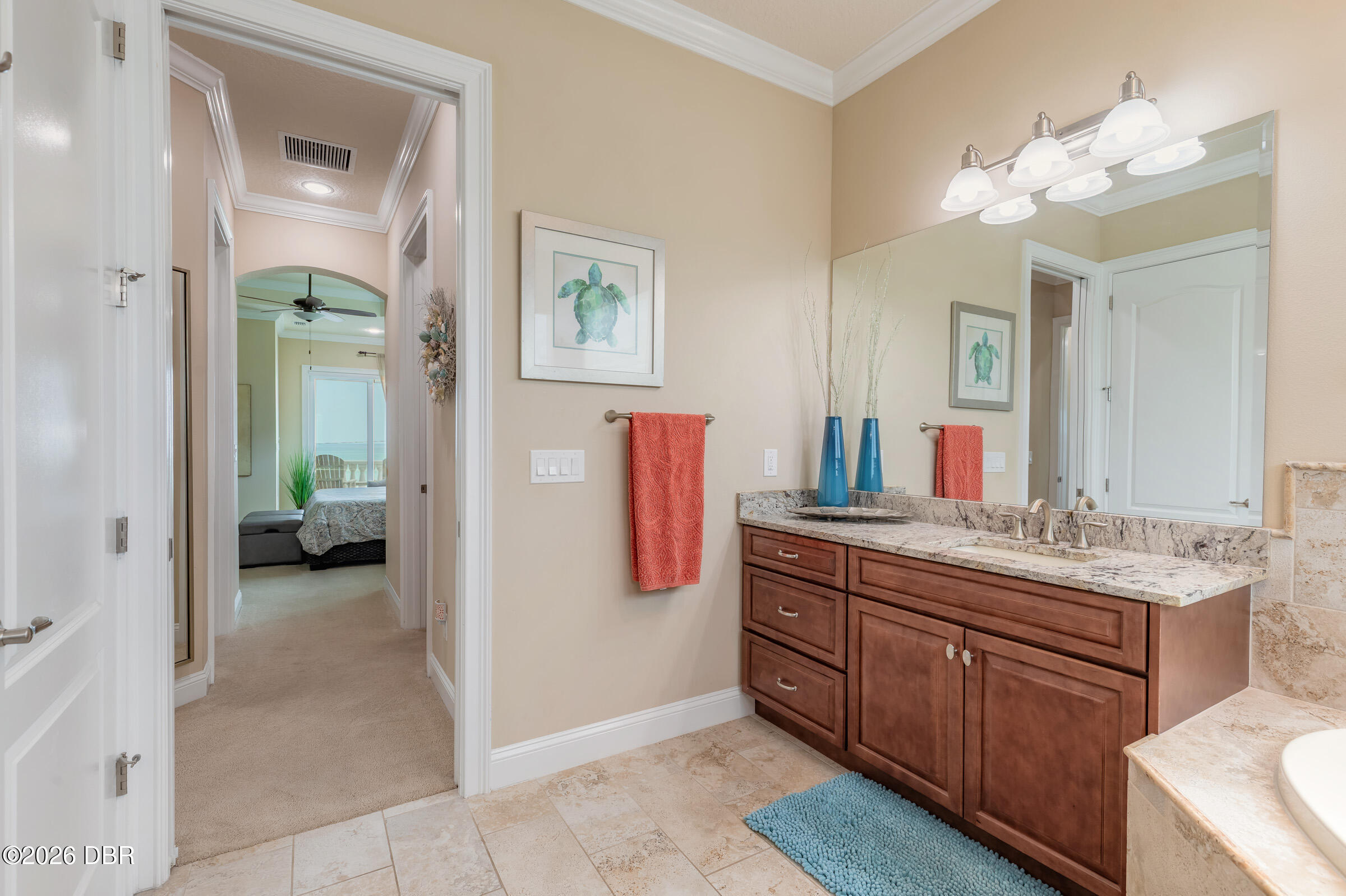 Bathroom with a granite countertop, dark wood vanity, large mirror, and coral towels.