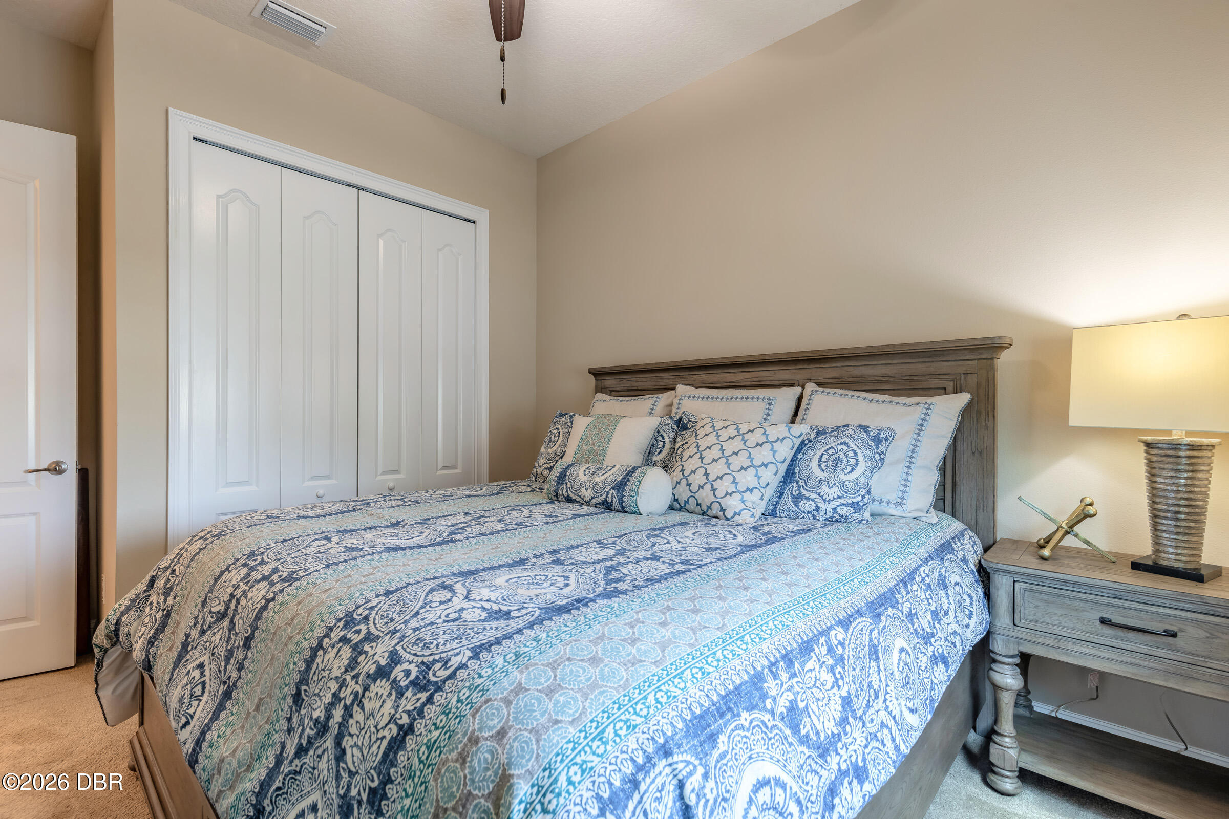 Bedroom with blue-and-white patterned bedding, a gray wood headboard, and a matching bedside table.