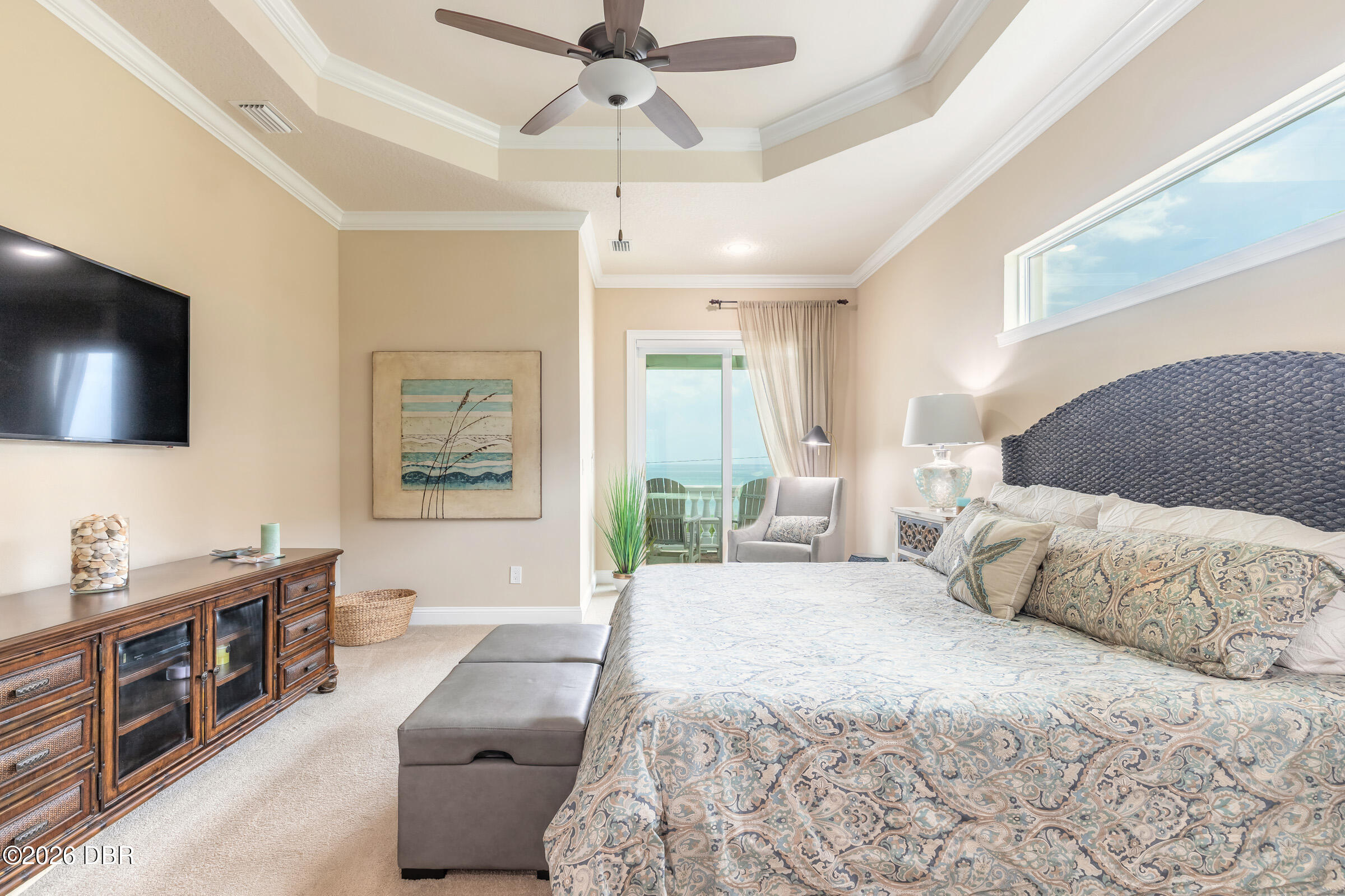 Furnished bedroom with a patterned bed, sliding glass doors, and an ocean view.