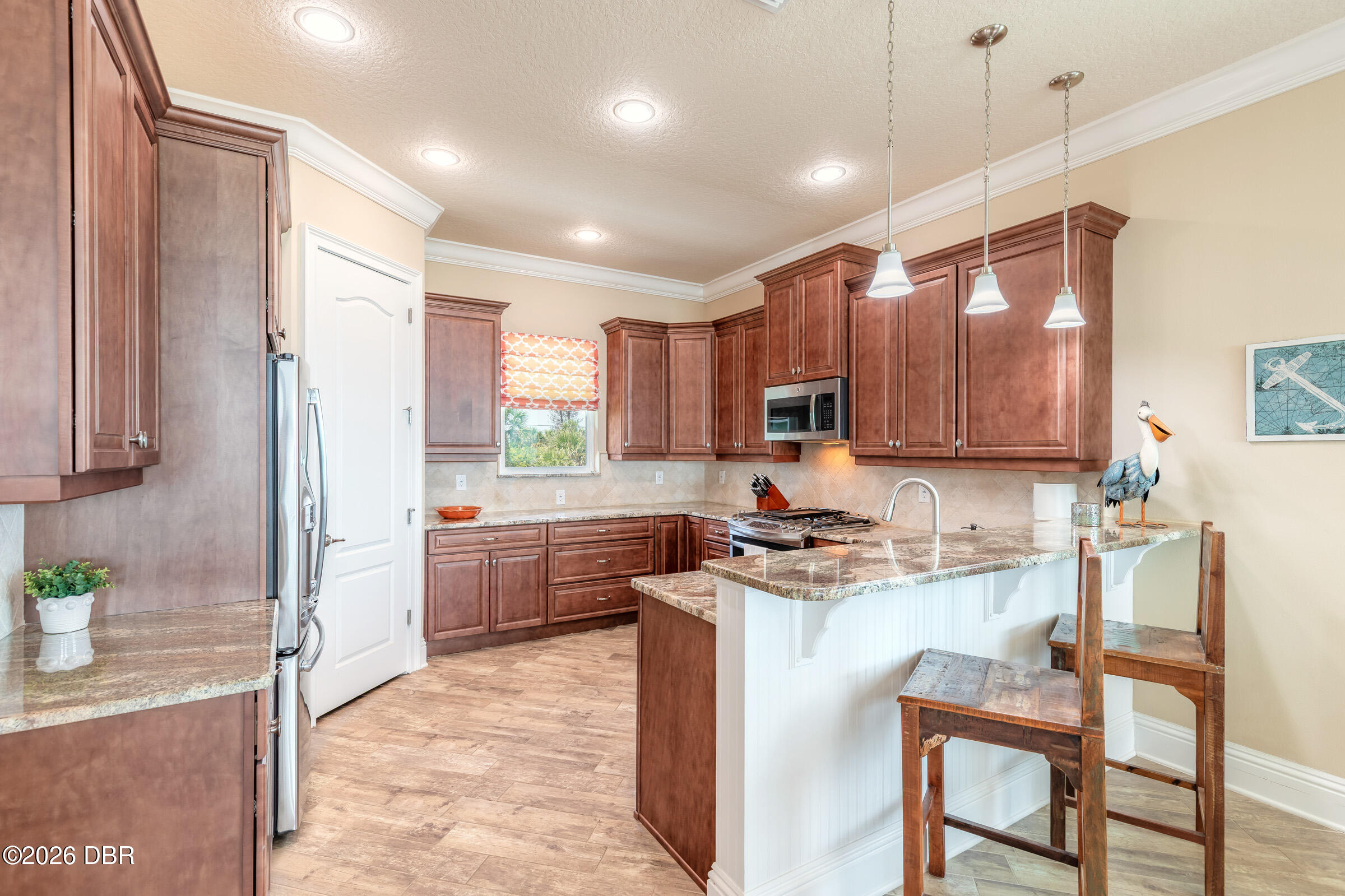 Kitchen with reddish-brown cabinets, granite counters, and a white island with wooden bar stools.