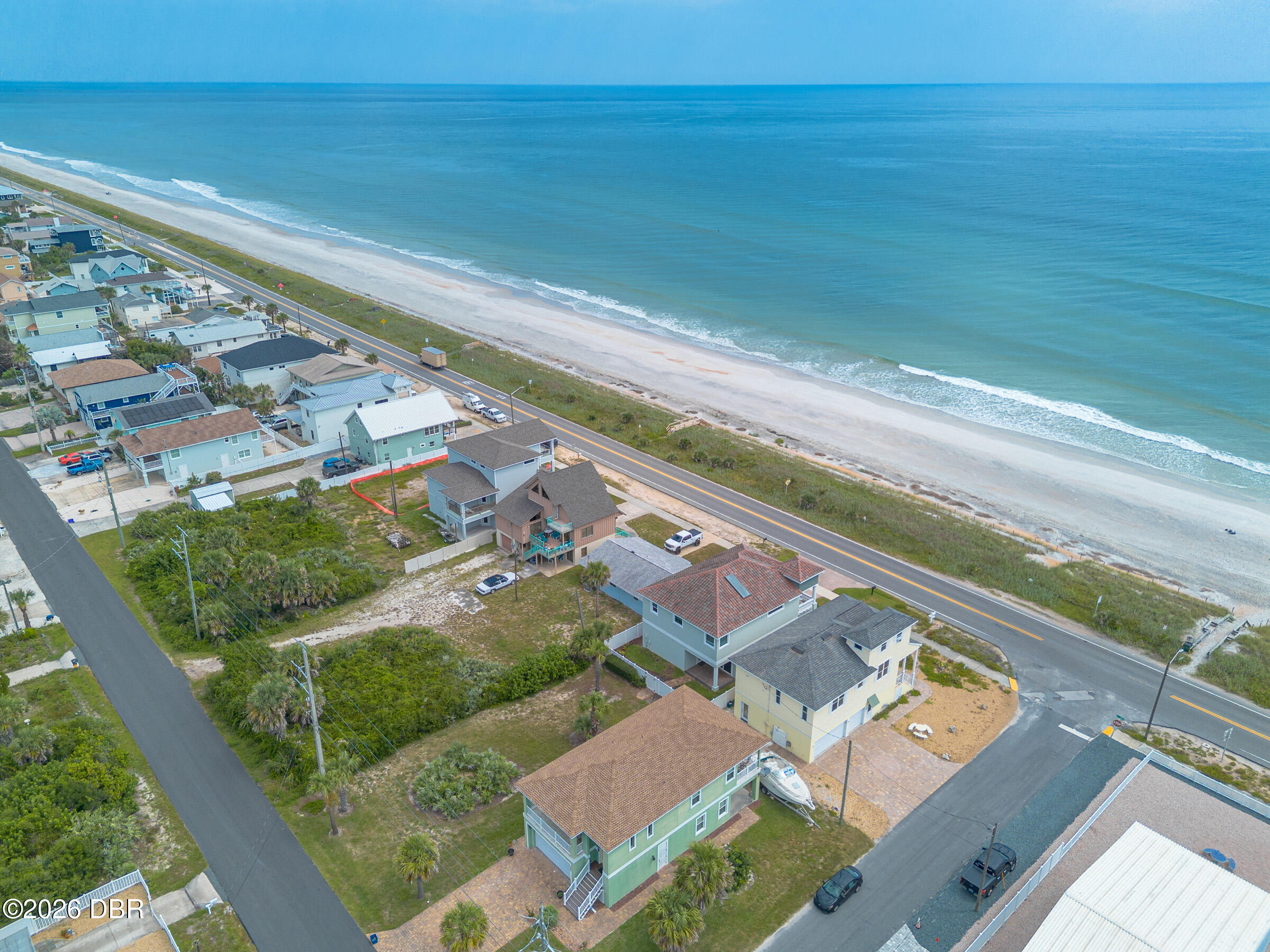 Aerial view of coastal homes along the beach, with the ocean beyond.