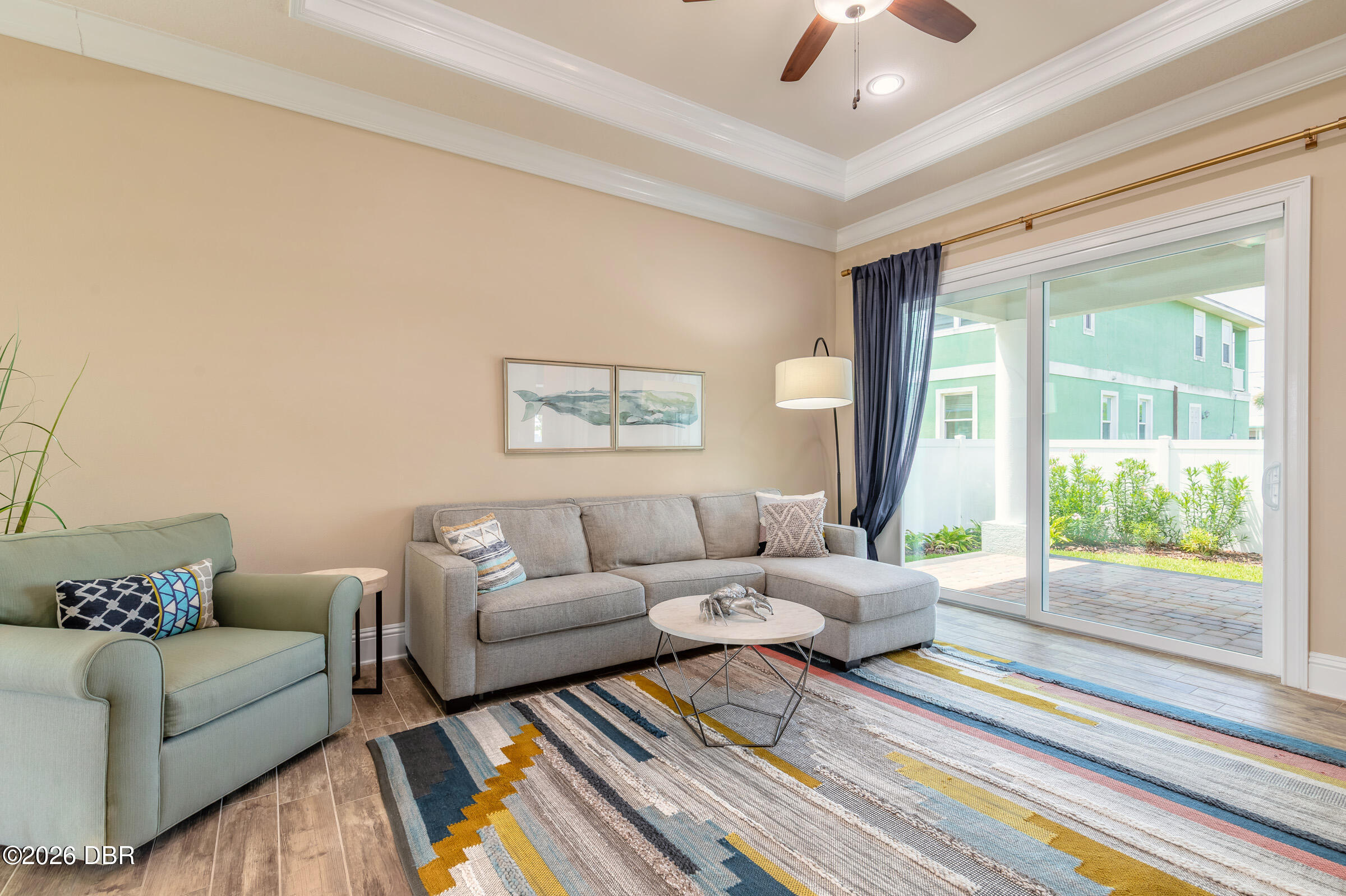 Living room with a gray sectional, colorful rug, and sliding glass doors to a patio.