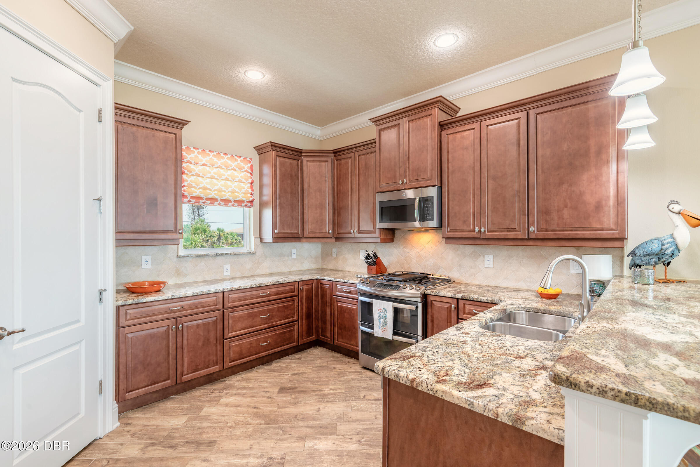 Kitchen with reddish-brown cabinets, granite counters, a large island, and stainless steel appliances.