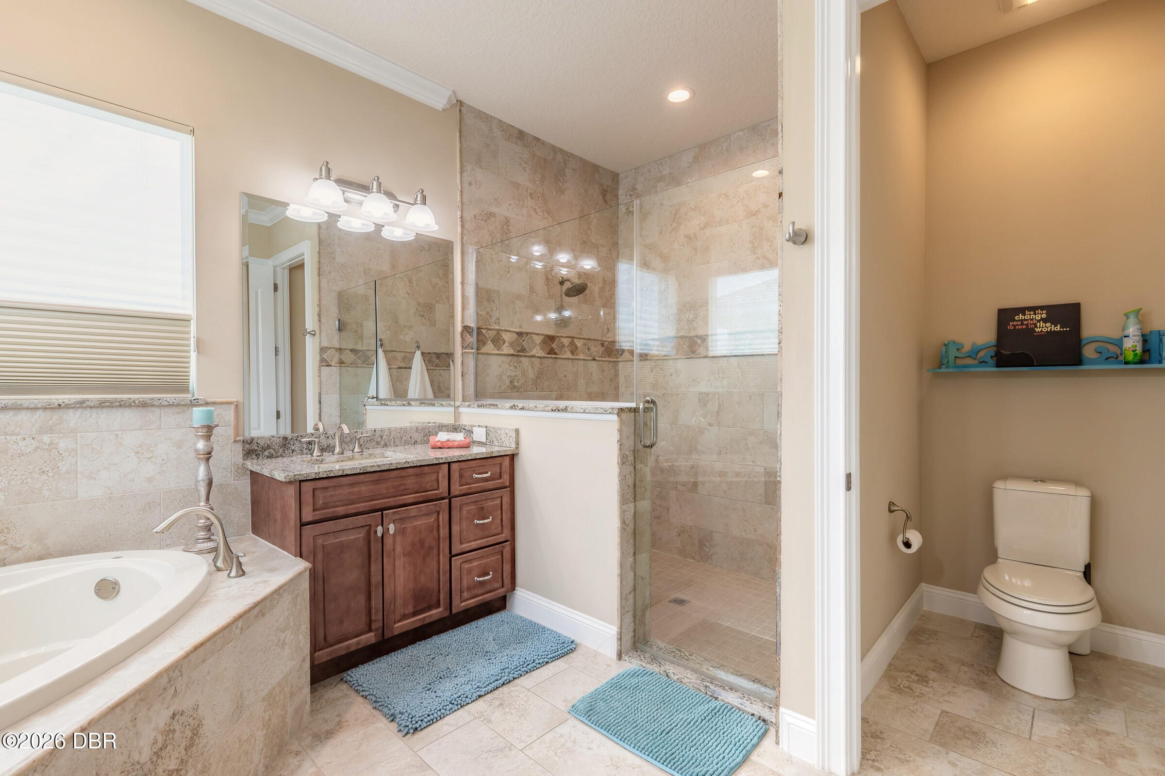 Bathroom with a glass shower, built-in tub, dark wood vanity, and separate toilet area.