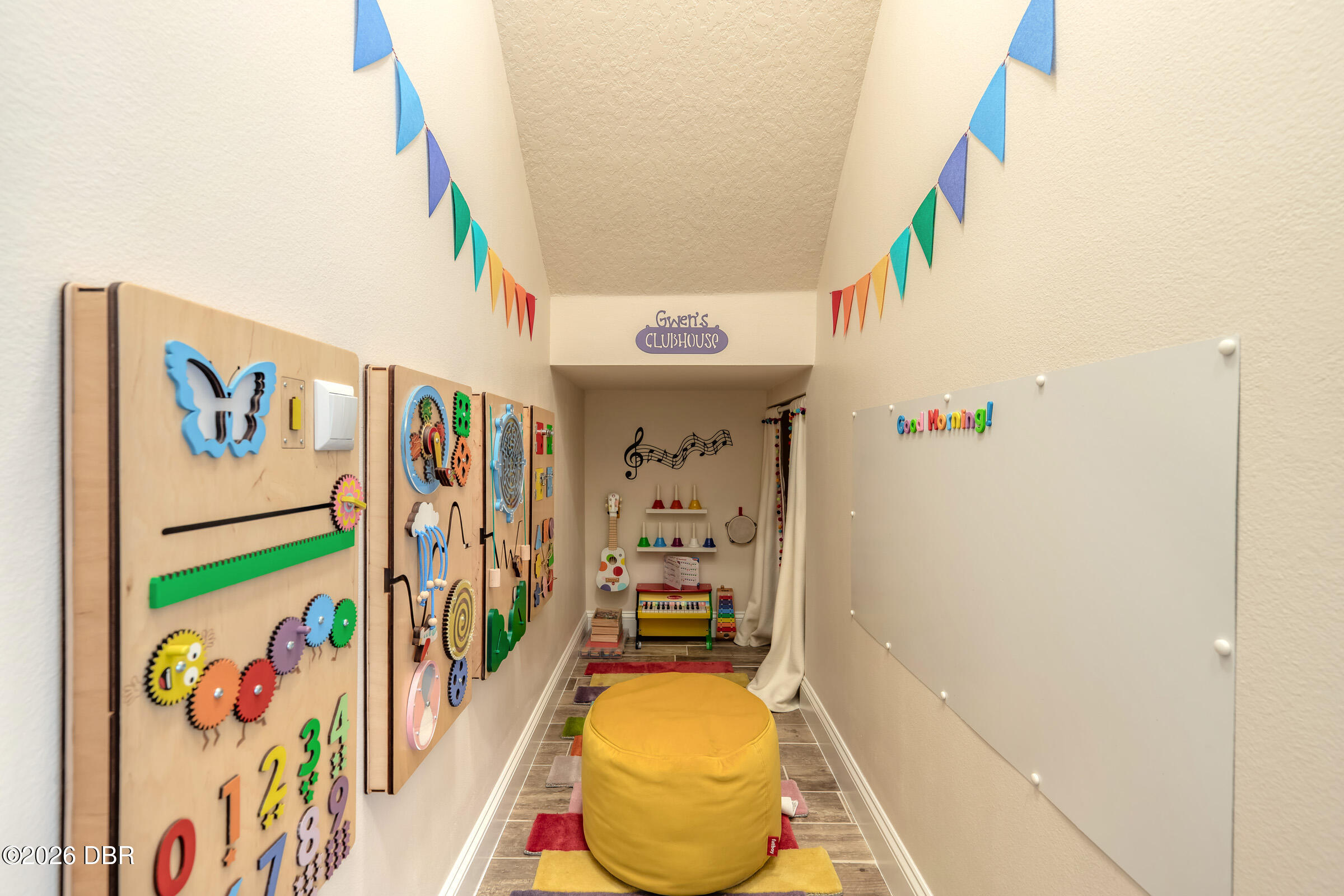 Children's playroom with colorful sensory wall panels, musical toys, and a yellow ottoman.