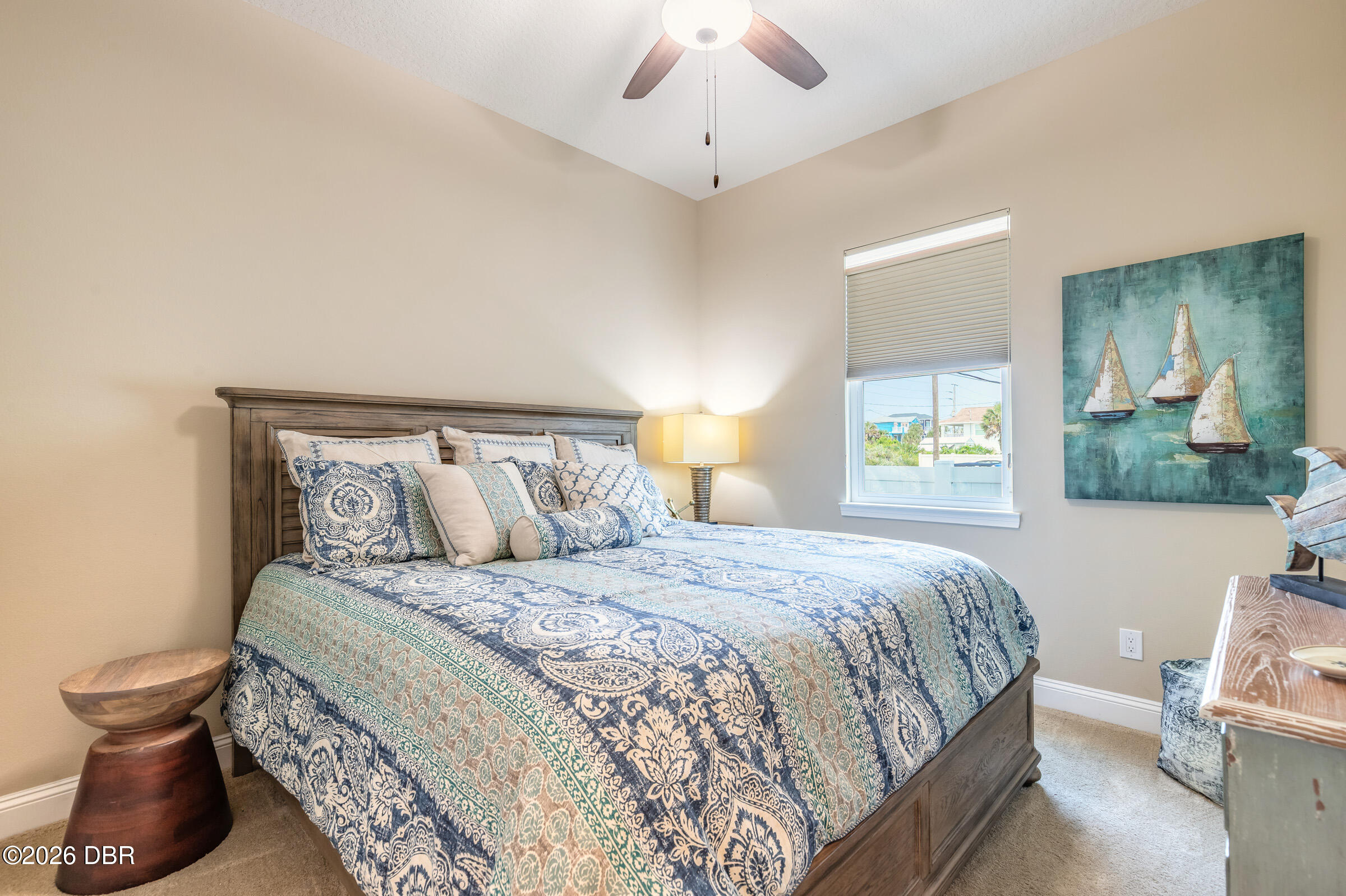 Furnished bedroom with blue patterned bedding, a dark wood bed, and sailboat artwork.