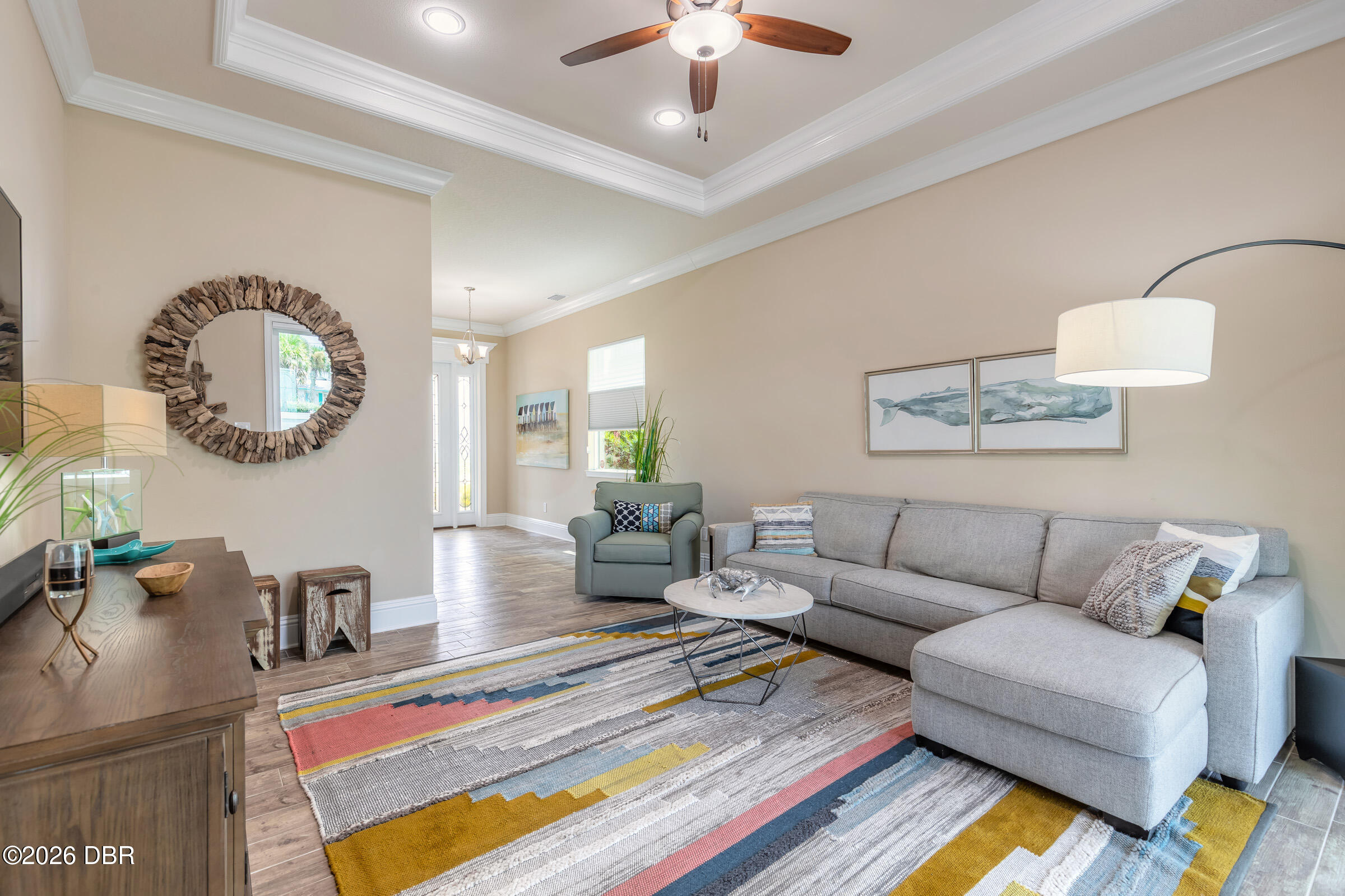 Living room with a gray sectional, colorful striped rug, and driftwood-framed mirror.