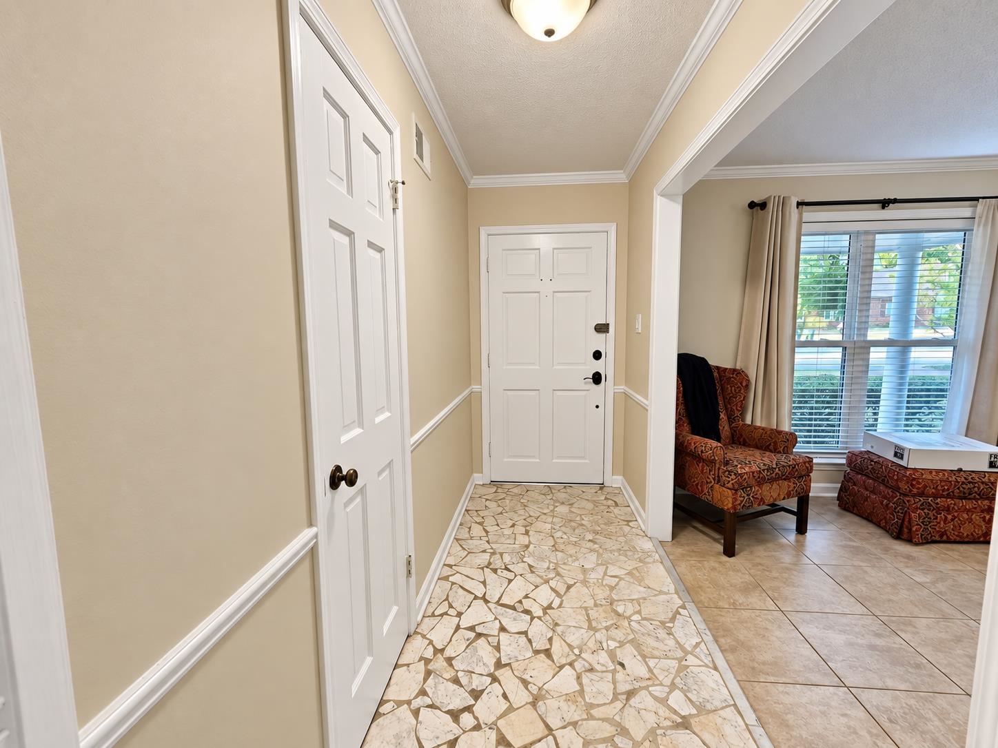 Entry foyer with a white front door, stone-pattern flooring, and a view into a sitting area.