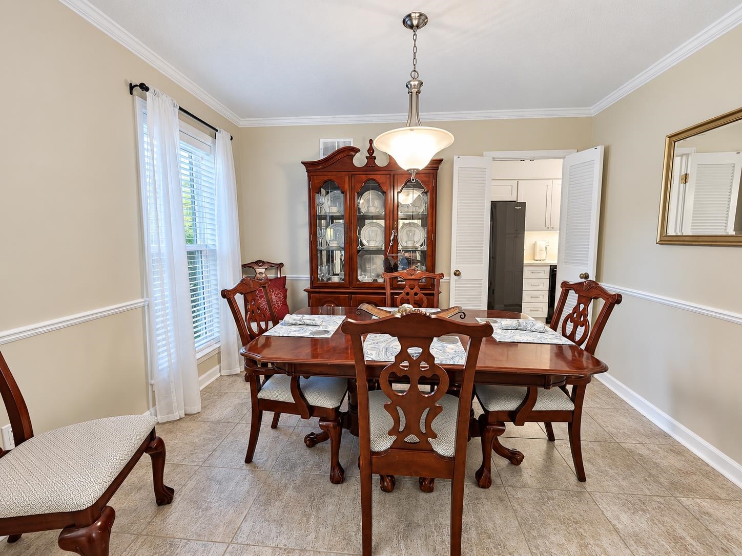 Dining room with a polished wooden table, carved chairs, and a glass-front china cabinet.