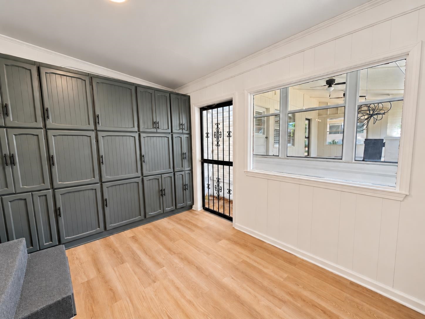 Interior room with dark gray built-in cabinets, light wood flooring, and a large window to an adjacent porch.