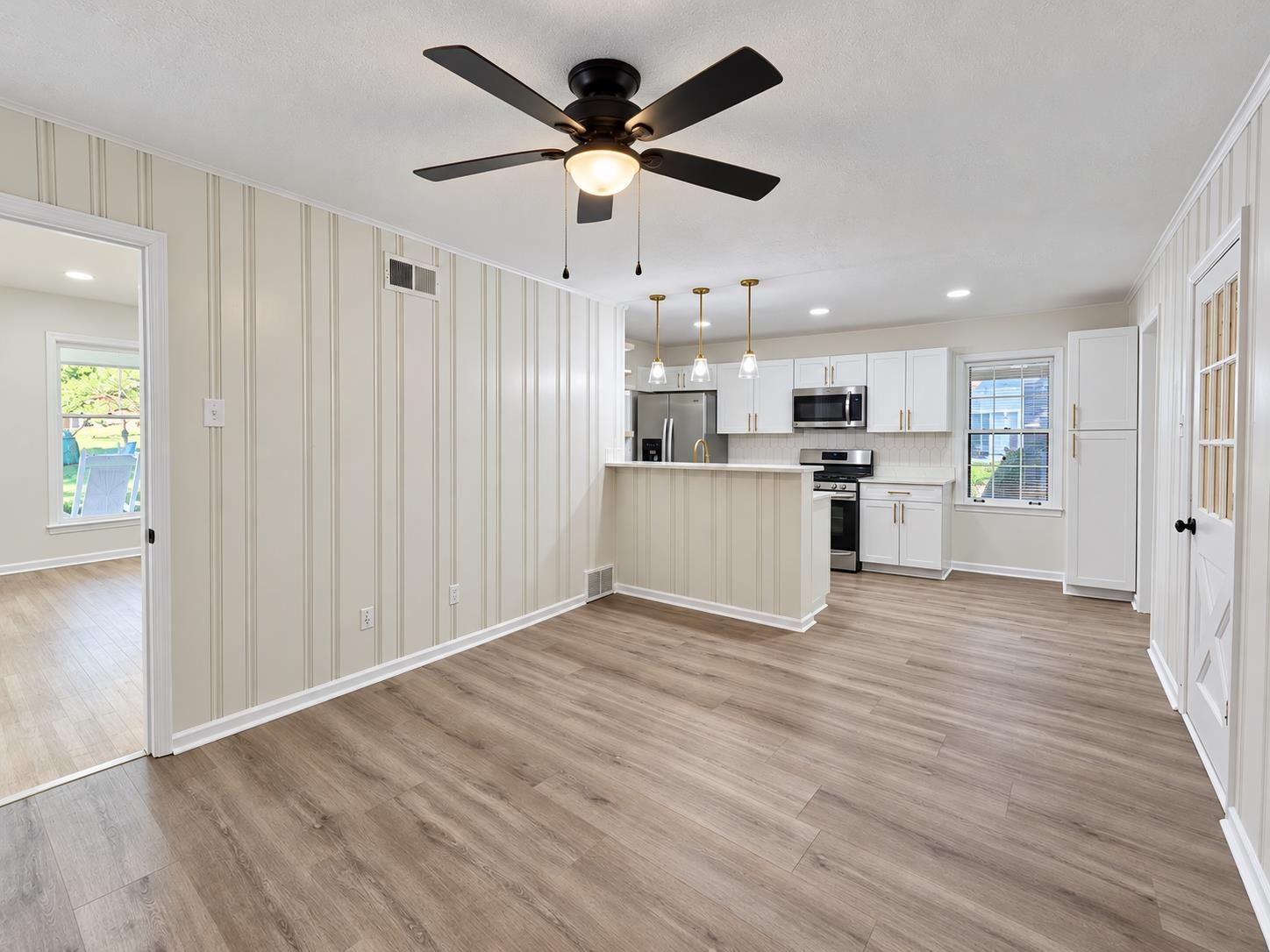Kitchen with white cabinets, stainless steel appliances, breakfast bar, and light wood-look flooring.