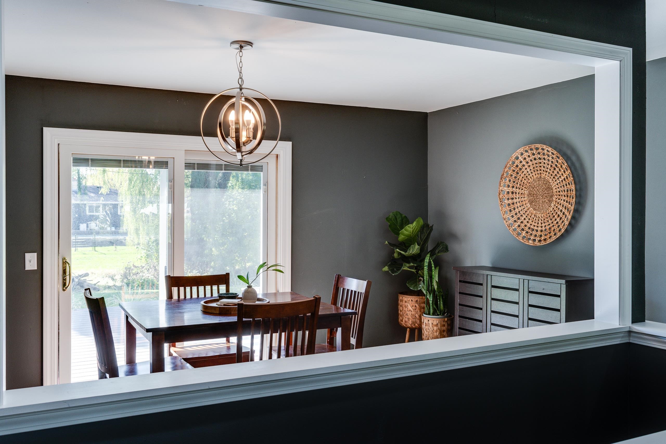 Dining room with a wooden table, globe pendant light, and glass doors opening to a deck.